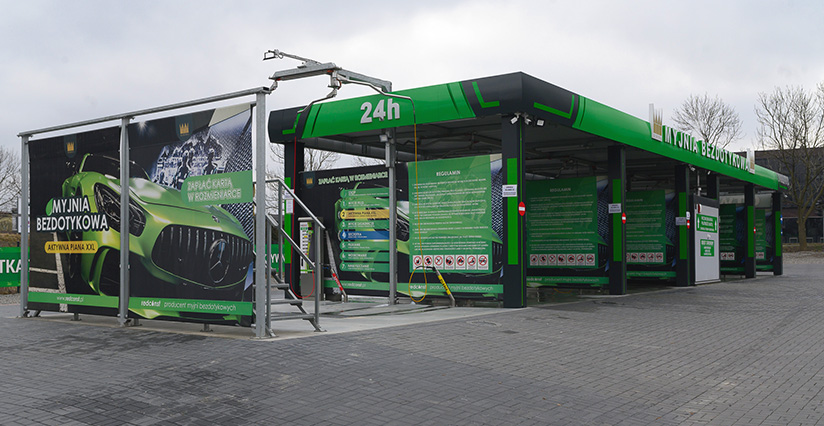 Bezdotykowa myjnia samochodowa 24h z nowoczesnymi stanowiskami. Na ścianach znajdują się informacje o korzystaniu z myjni. Przyciągający wzrok zielony design z grafiką samochodu. Idealne rozwiązanie dla właścicieli pojazdów szukających efektywnego czyszczenia.